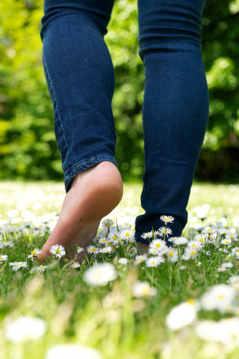 photo of barefoot young woman walking through field