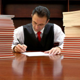photo of an attorney sitting at table next to stacks of reports