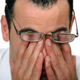 photo of tired man rubbing his eyes