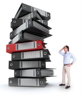 Information overload - man next to big stack of reports