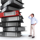 Information overload - man next to big stack of reports