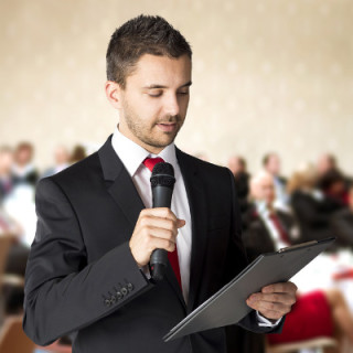 photo of man speaking into microphone at a public meeting.