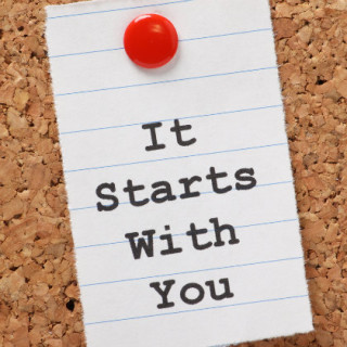 the words "It Starts With You" tacked to a bulletin board